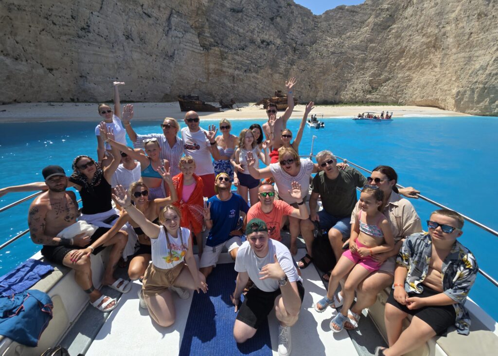 Grupa turystów podczas rejsu Magic Tours do Zatoki Wraku na Zakynthos, na tle turkusowego morza i słynnego wraku statku