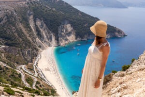 Kobieta w białej sukience podziwia plażę Myrtos na Kefalonii z turkusowym morzem – Grecja 2026
