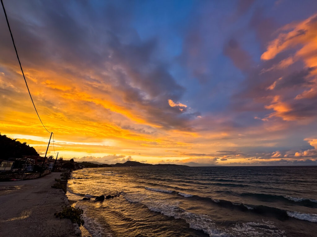 Zachód słońca nad morzem w Argassi na Zakynthos z pomarańczowo-różowym niebem i falami przy brzegu