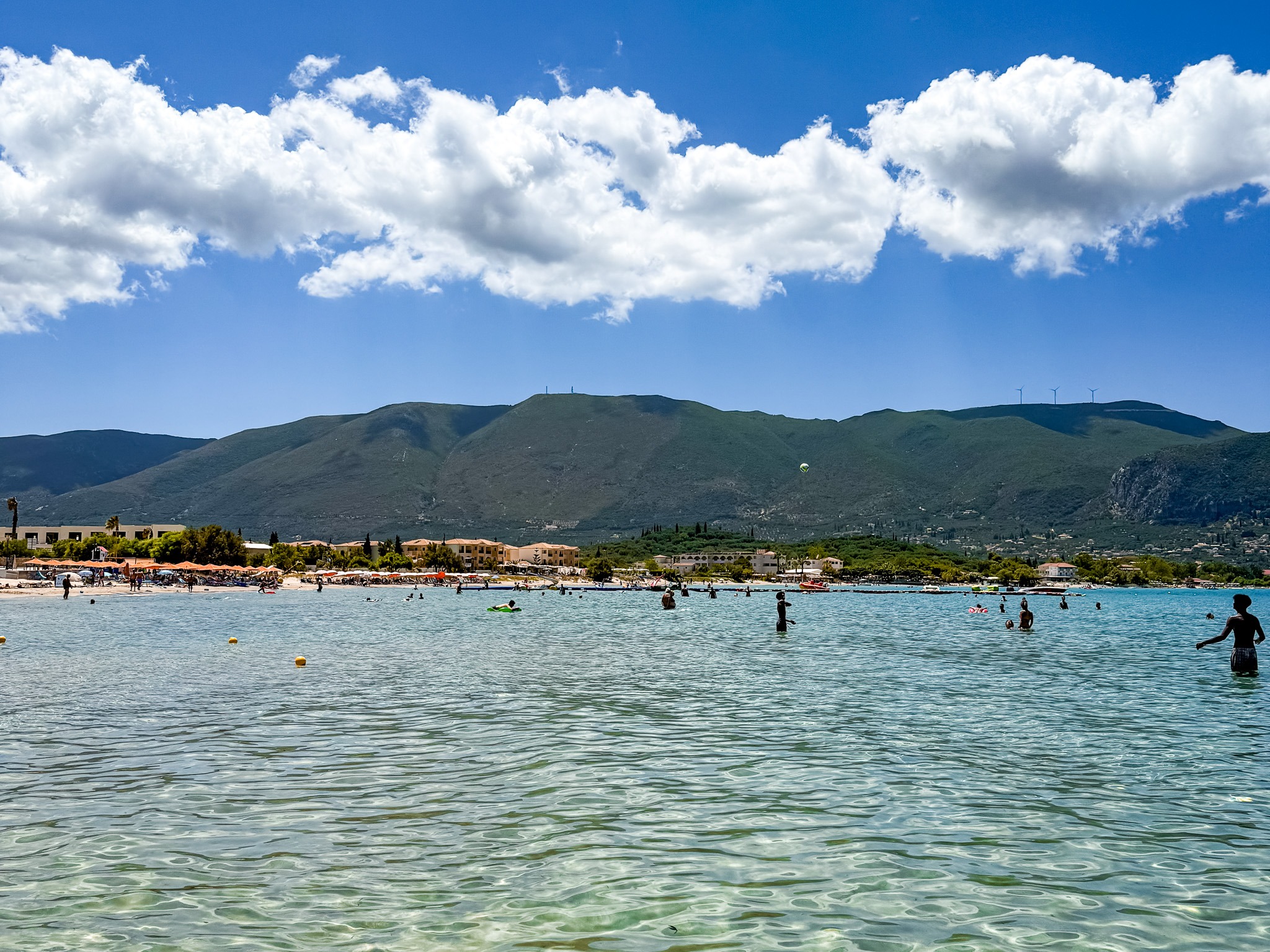 Plaża Alykanas na Zakynthos z płytką, turkusową wodą i widokiem na góry w tle