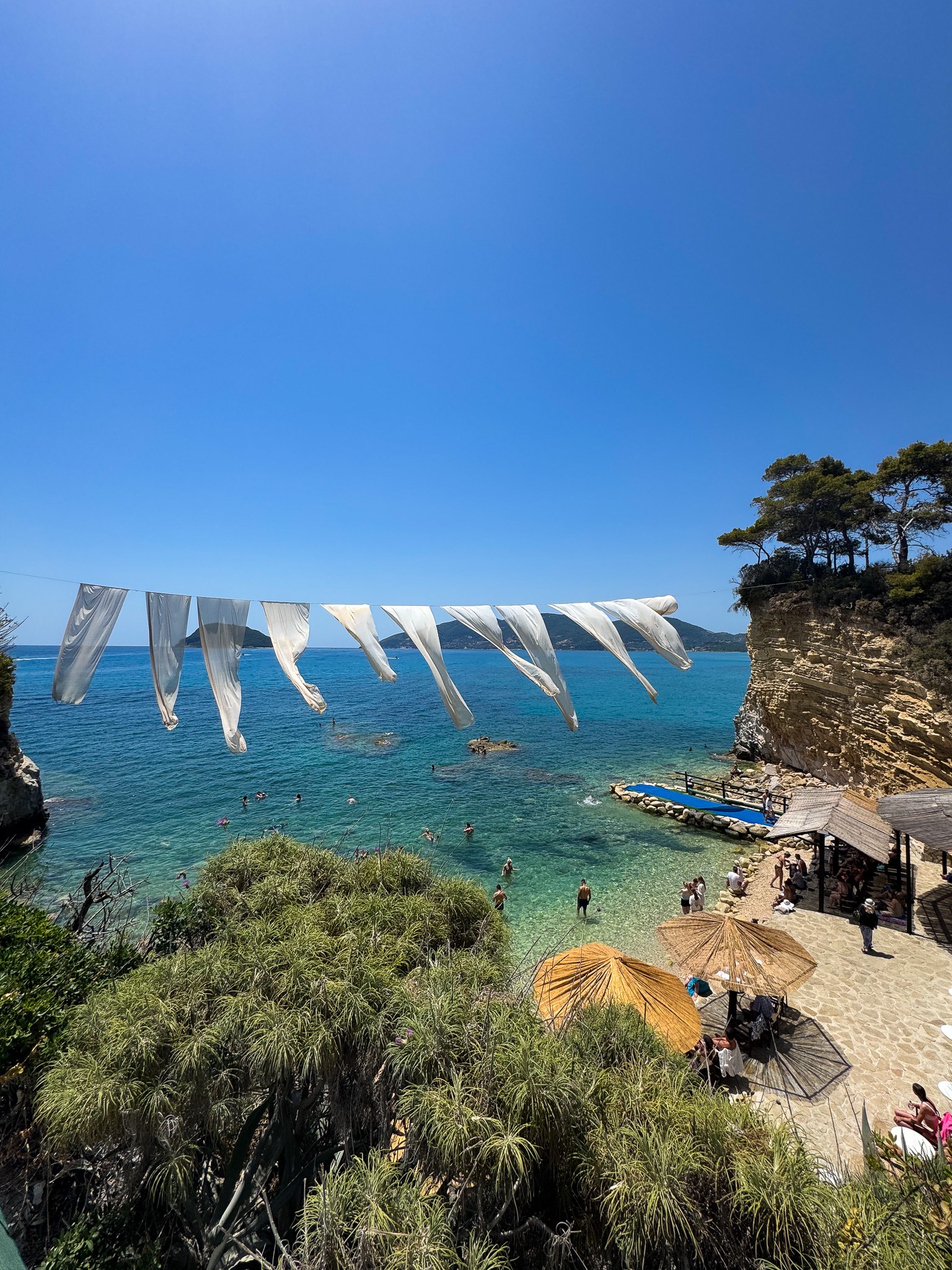 Widok na wyspę Cameo na Zakynthos z białymi flagami i turkusową wodą