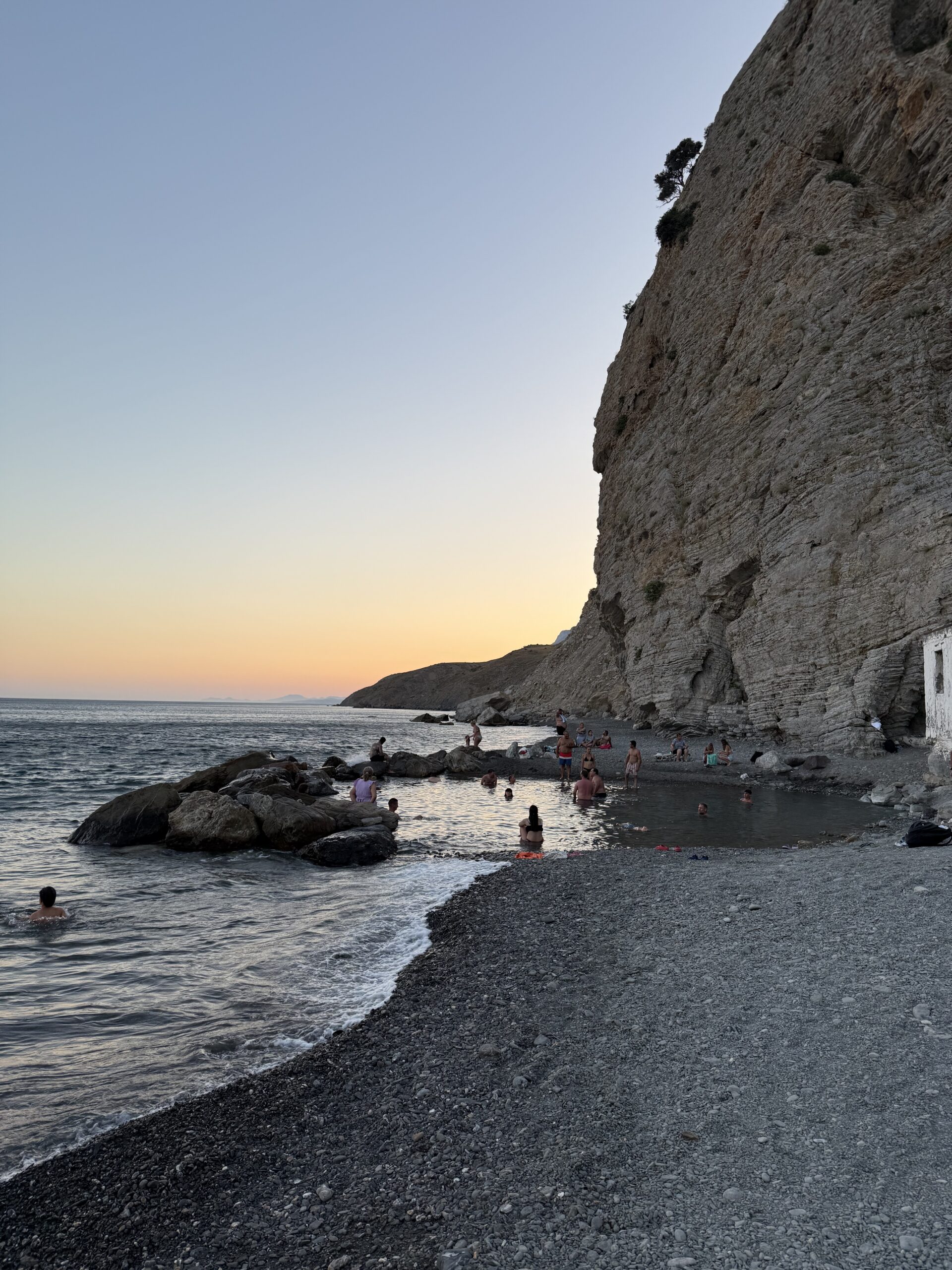 Naturalne termy na Kos o zachodzie słońca z kąpiącymi się turystami