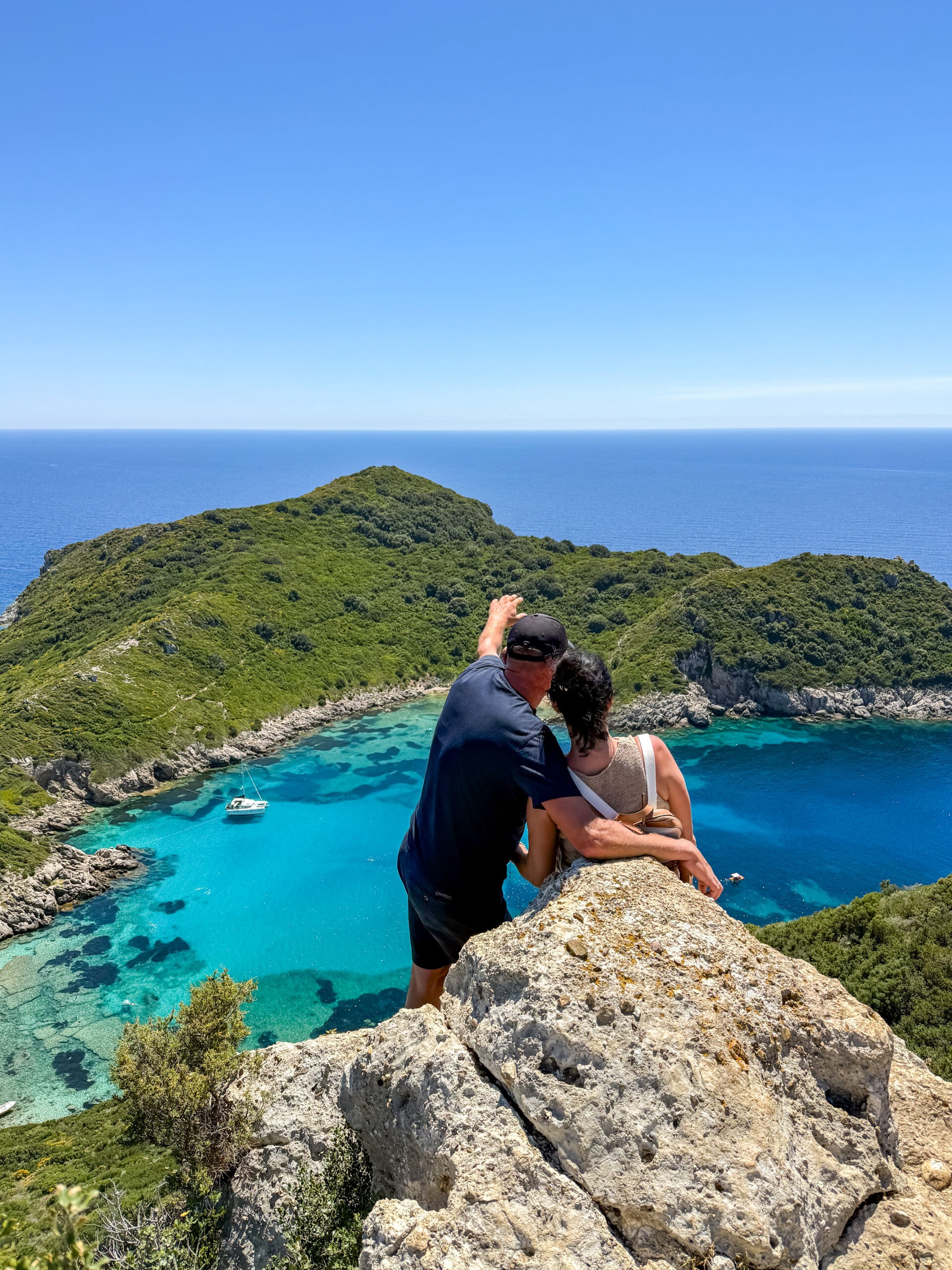 Para podziwia widok na Porto Timoni na Korfu z punktu widokowego nad turkusową zatoką