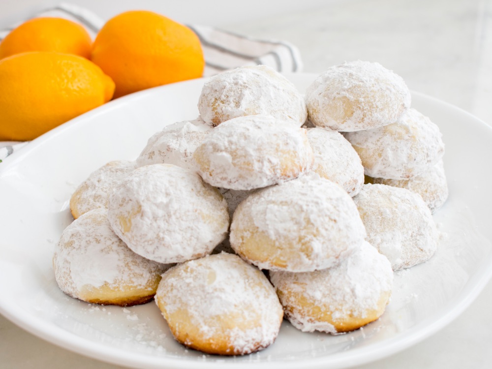 Greckie ciasteczka Kourabiedes obsypane cukrem pudrem na talerzu, tradycyjny świąteczny wypiek.