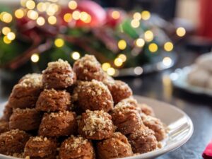 Greckie świąteczne ciasteczka Melomakarona ułożone na talerzu, w tle dekoracje bożonarodzeniowe.