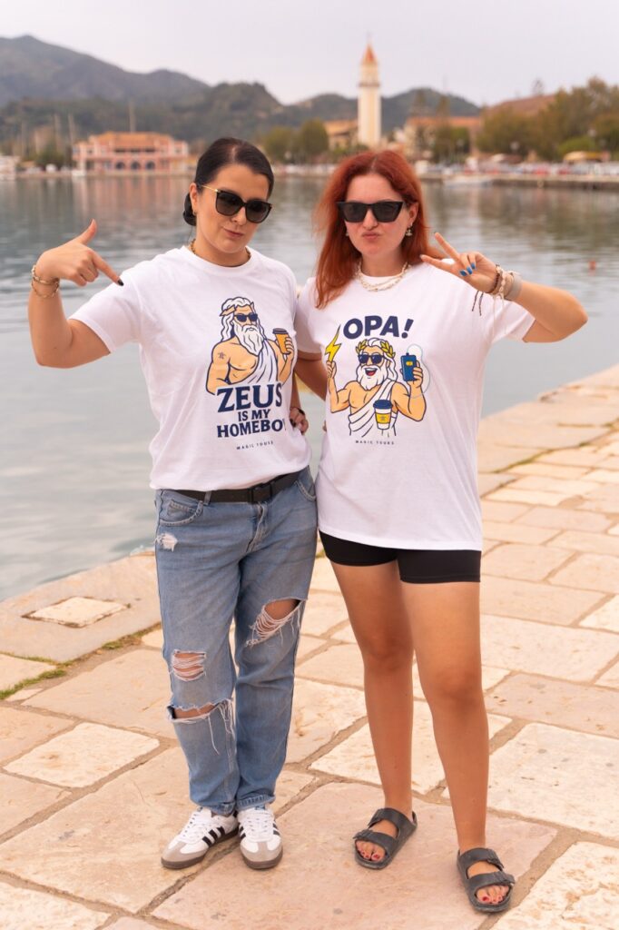 Kobiety w koszulkach Zeus Is My Homeboy i OPA – greckie ubrania Magic Tours.