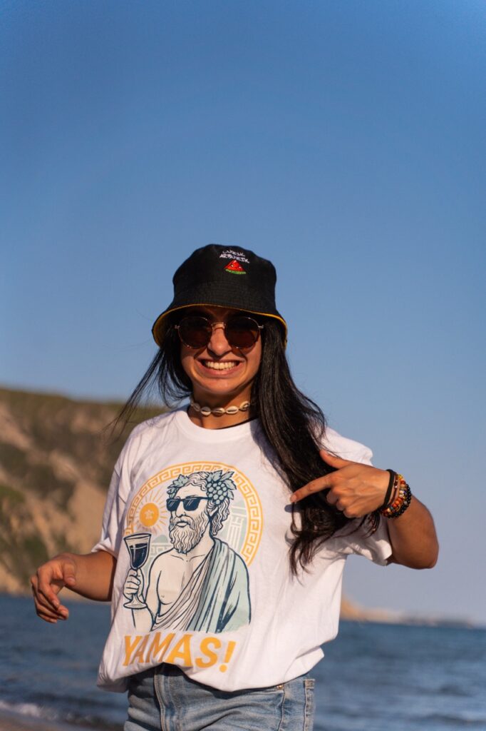 Kobieta w koszulce Yamas Magic Tours na plaży w Grecji.