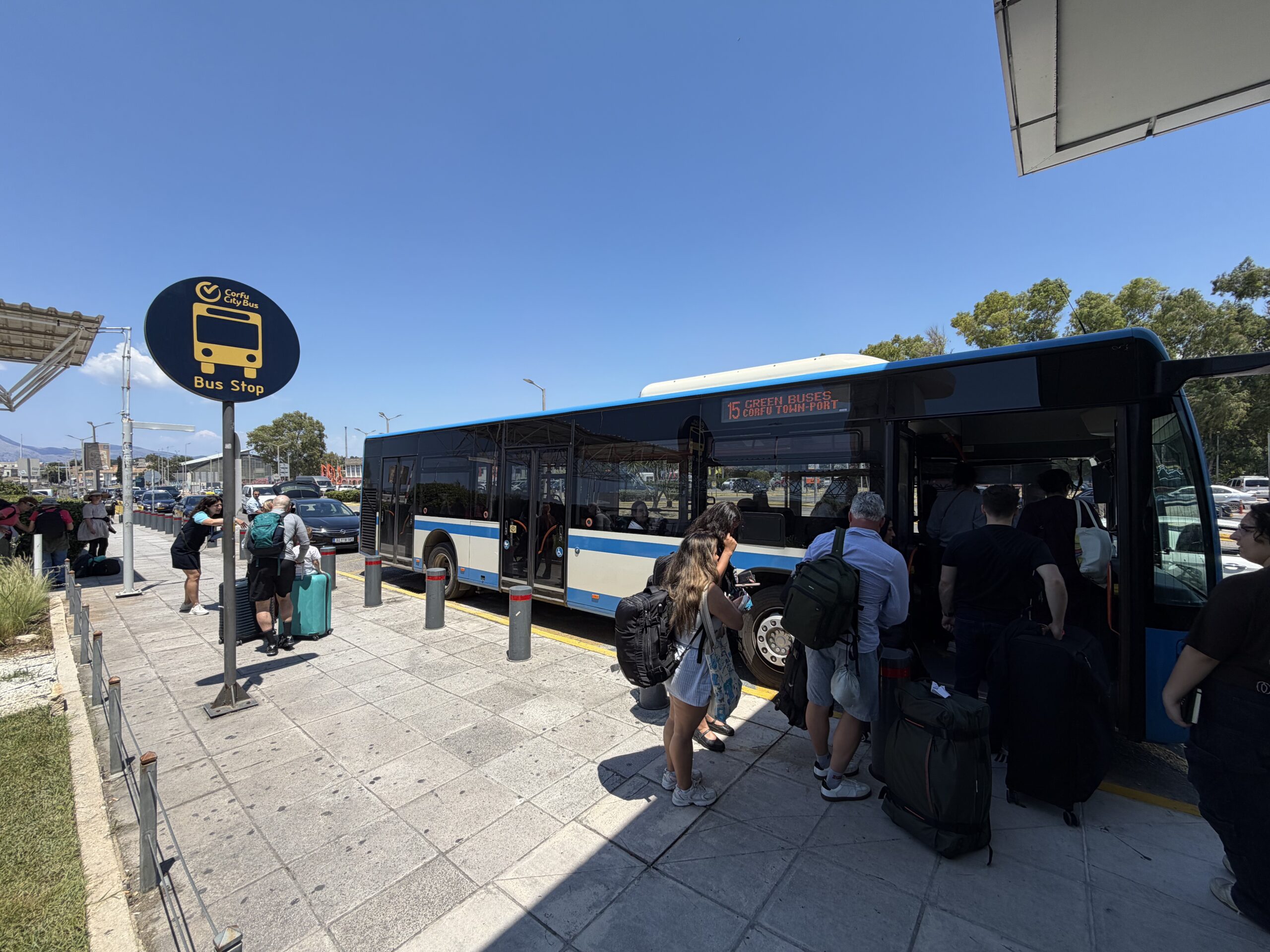 Niebieski autobus linii 15 podczas wsiadania pasażerów na przystanku komunikacji miejskiej na Korfu