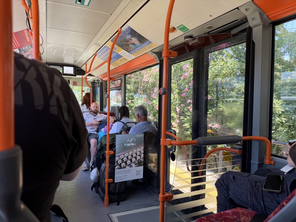 Wnętrze niebieskiego autobusu miejskiego podczas przejazdu przez zielone okolice Korfu